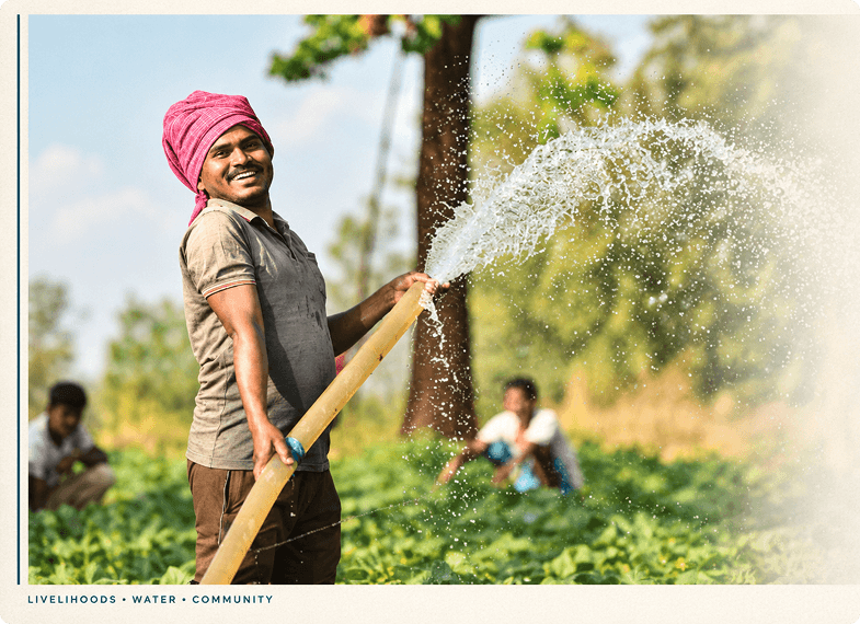 A farmer smiling while watering a field with a hose, under the caption Livelihoods, Water, Community