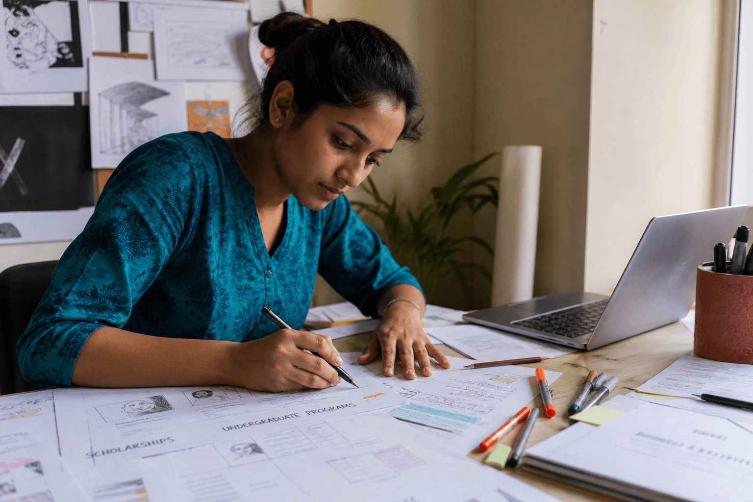 Indian designer sketching education brochure layouts